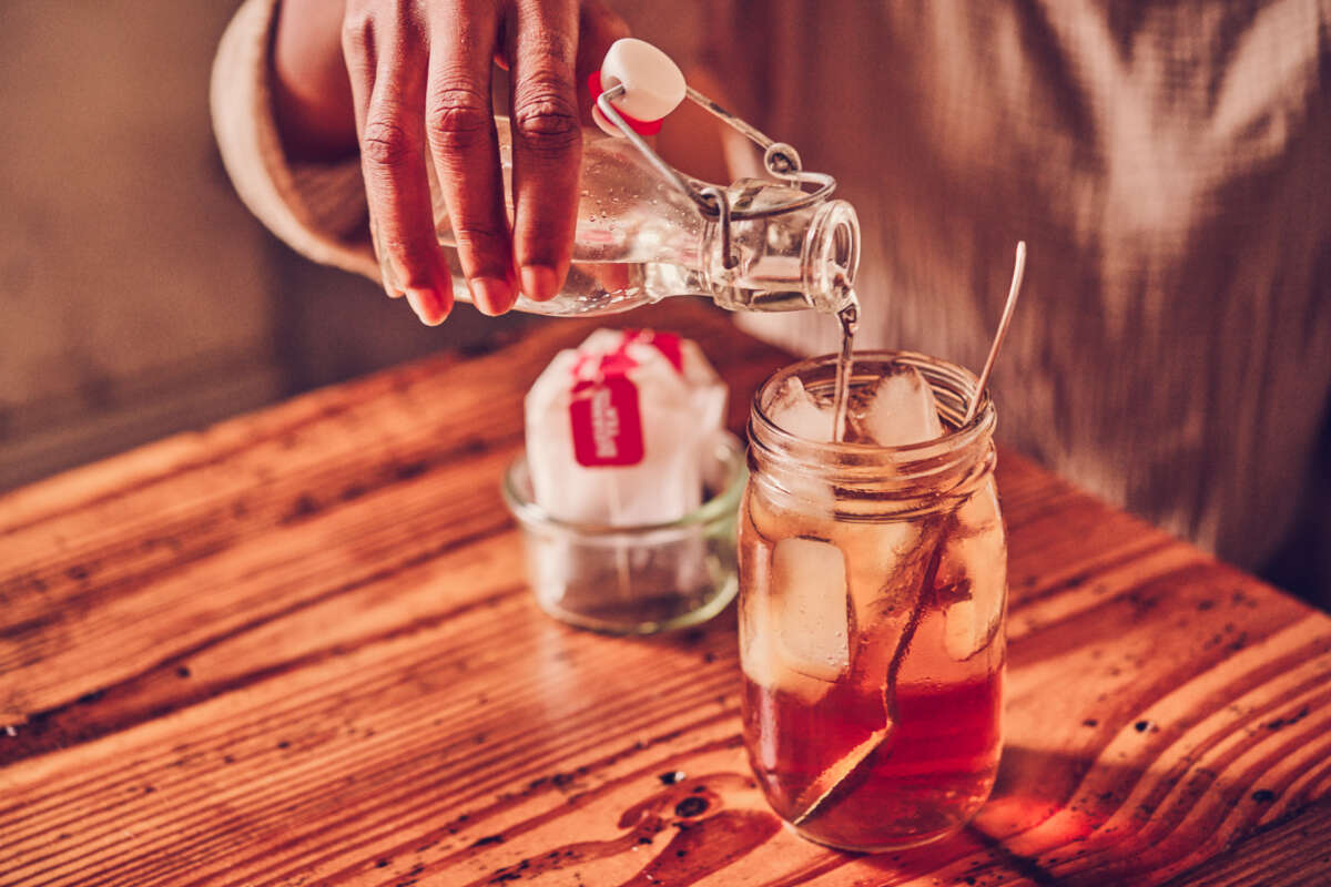Pouring simple syrup into a glass of iced tea