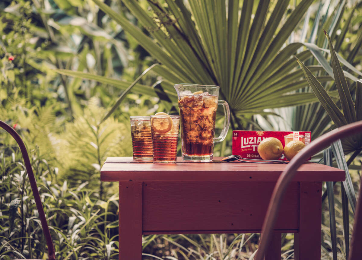 Iced tea pitcher and glasses on a table outside with palm trees