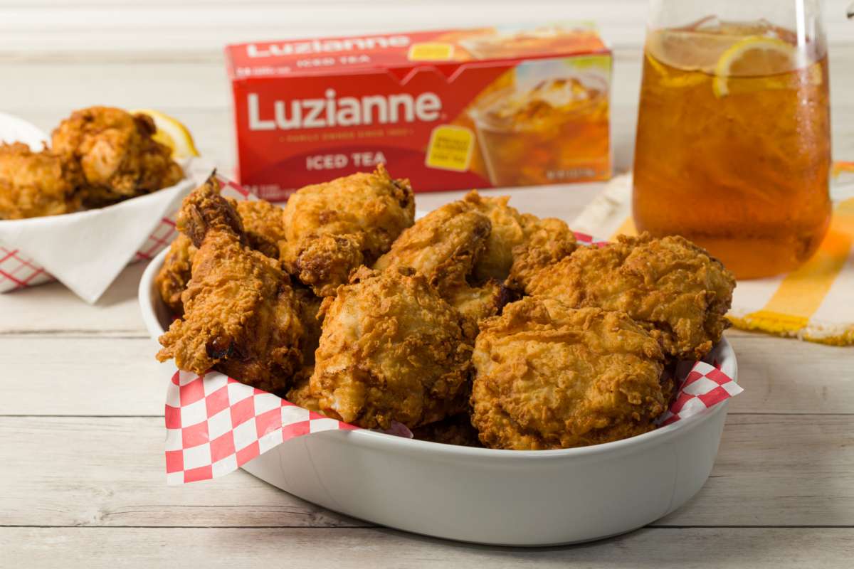 Tea Brined Crispy Fried Chicken in a serving dish with box of Luzianne Iced Tea bags in background