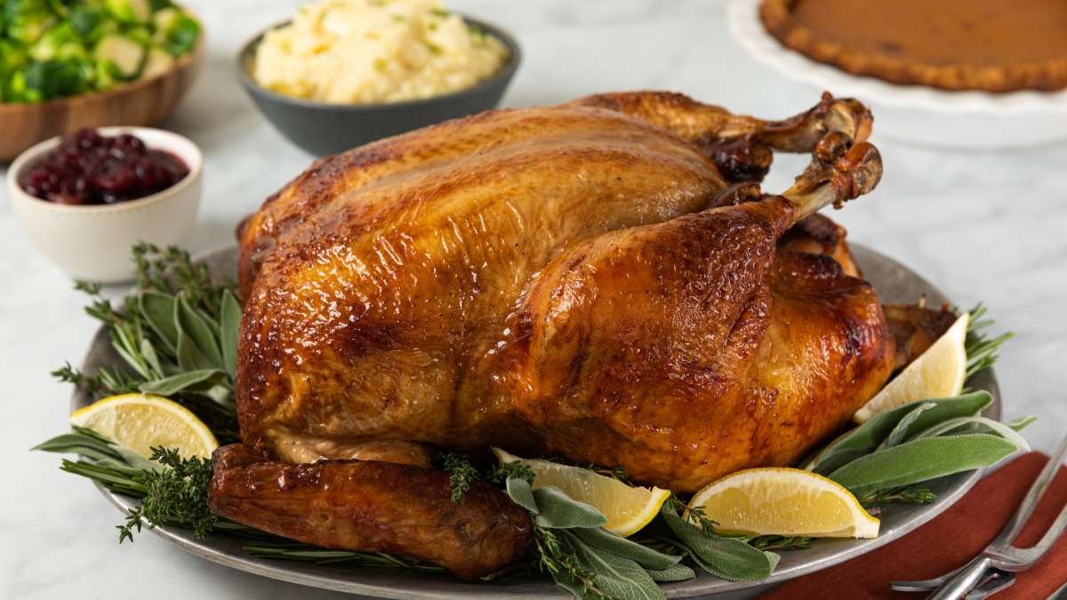 Tea Brined Turkey with Bourbon and Luzianne Sweet Tea on a serving platter with peas and mashed potatoes in the background