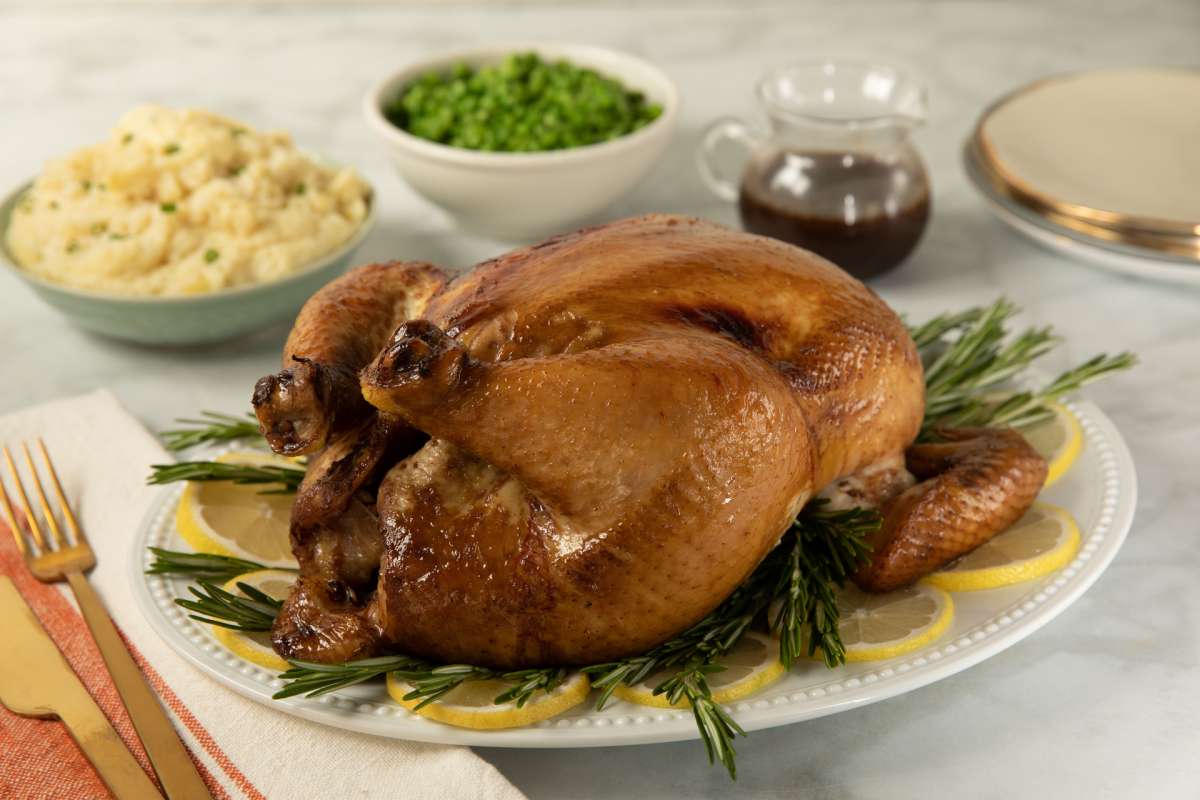 Tea Brined Turkey with Bourbon and Luzianne Sweet Tea on a serving platter with peas and mashed potatoes in the background