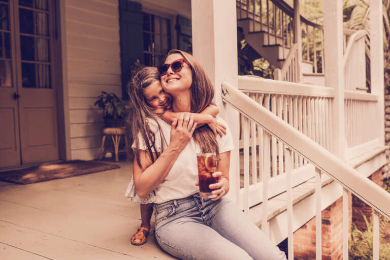 Mother and daughter relaxing on a Southern front porch with glass of iced tea