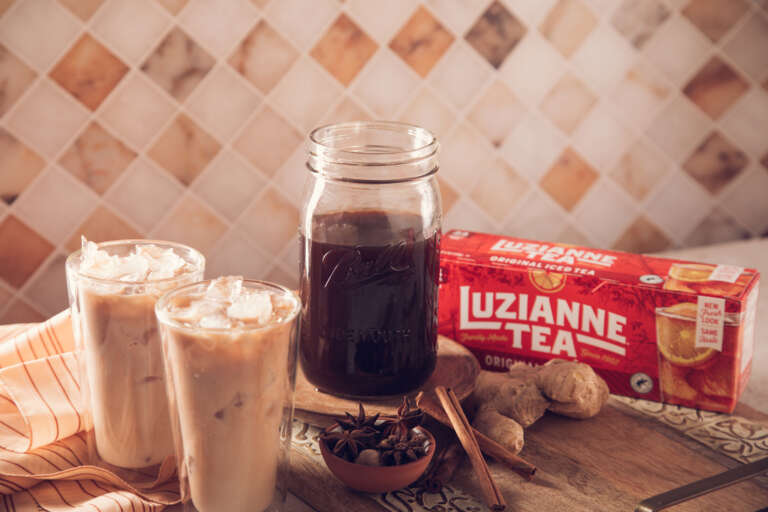Chai Tea Concentrate in storage jar and 2 glasses of chai iced tea with milk